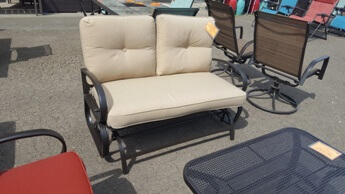 Outdoor Chocolate Metal Gliding Loveseat with Rounded Arms & Beige Cushions